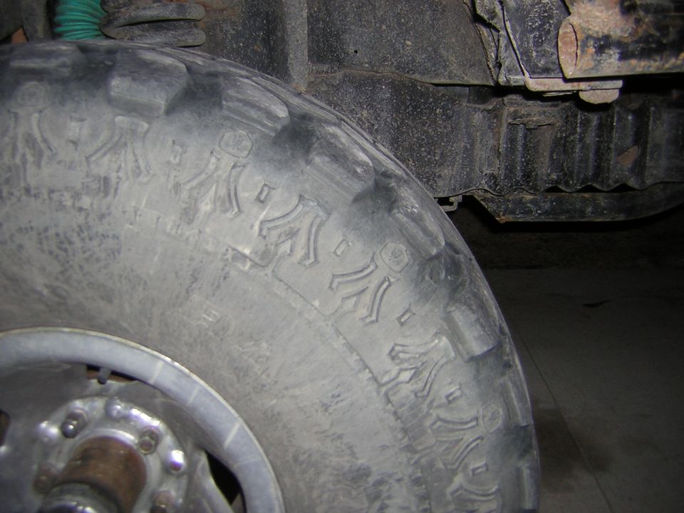Close-up of a tire with aggressive tread pattern and visible suspension components