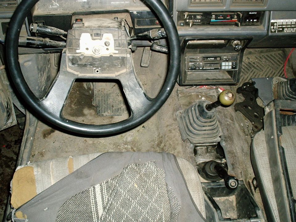 Dirty pickup interior with steering wheel, Alpine stereo, manual shifter and torn driver seat