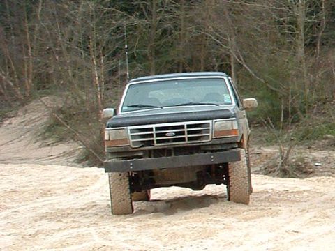 1993 Ford Bronco - This Ford Bronco is navigating a sandy path surrounded by trees.