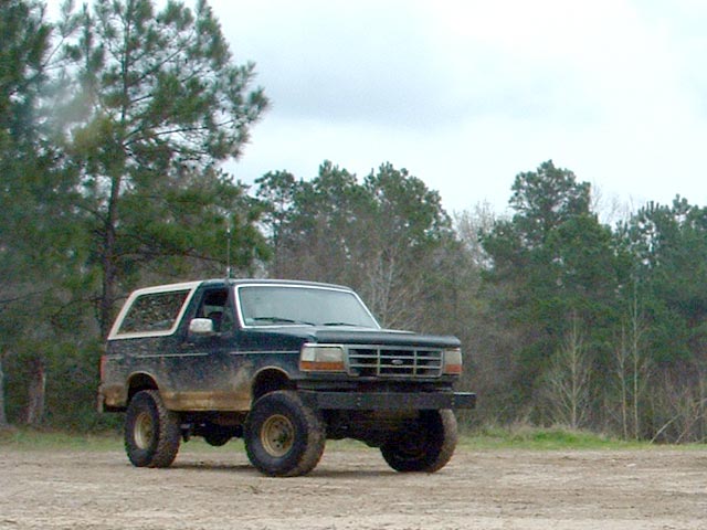 Dark blue and white Ford Bronco with mud splatters, seen from a 3/4 front angle