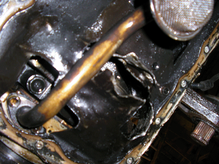 Close-up of an engine oil pan with a dipstick inserted