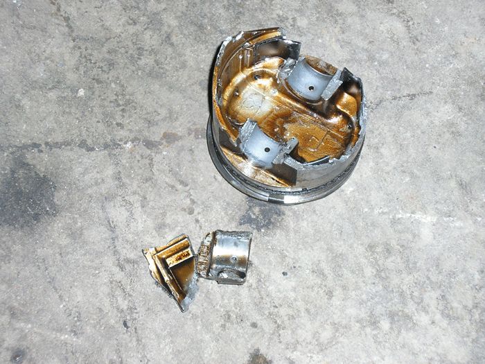 Engine component, possibly a distributor cap and rotor, lying on a concrete surface