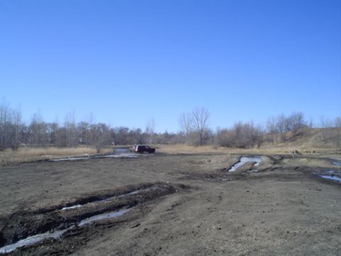 1981 Ford Bronco - An SUV navigates a challenging muddy track on a clear day.