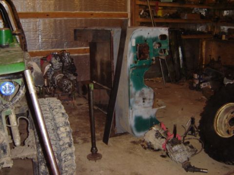 1992 Ford Bronco - Vehicle parts and a partial body panel are scattered around a garage with tools and tires.