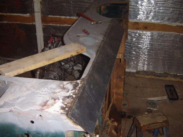 car body panel with rust and engine components visible underneath