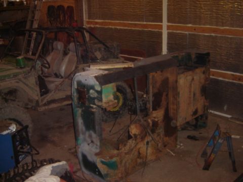 1992 Ford Bronco - A heavily rusted vehicle front end sits in a garage, revealing its interior and engine bay.