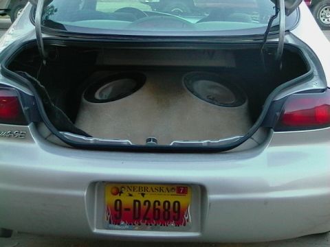1999 Ford Taurus - The trunk of a car is open, revealing a large custom subwoofer enclosure with two speakers.