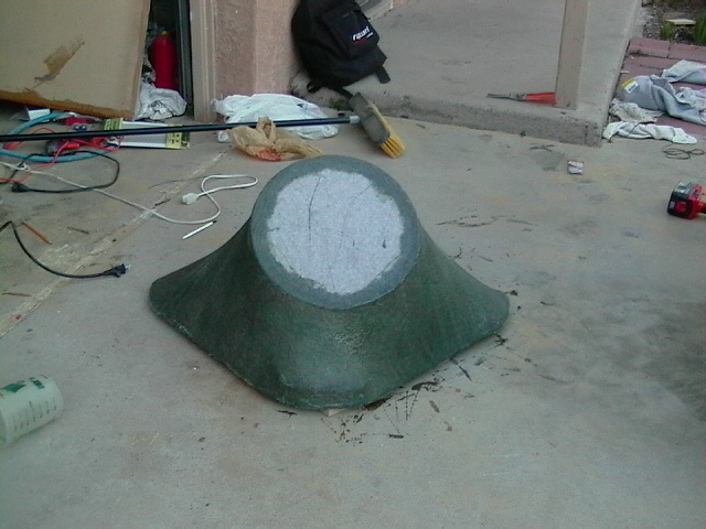 Green fiberglass part with circular top on concrete floor