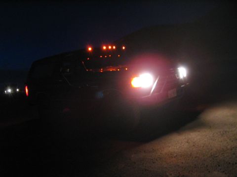 1991 Ford Bronco - A dark SUV is seen from the front at night with its headlights illuminated.