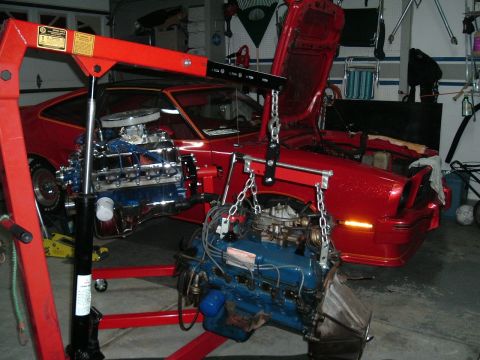 1978 Ford Mustang II - A red 1978 Ford Mustang II is in a garage, with its engine being removed by an engine hoist.