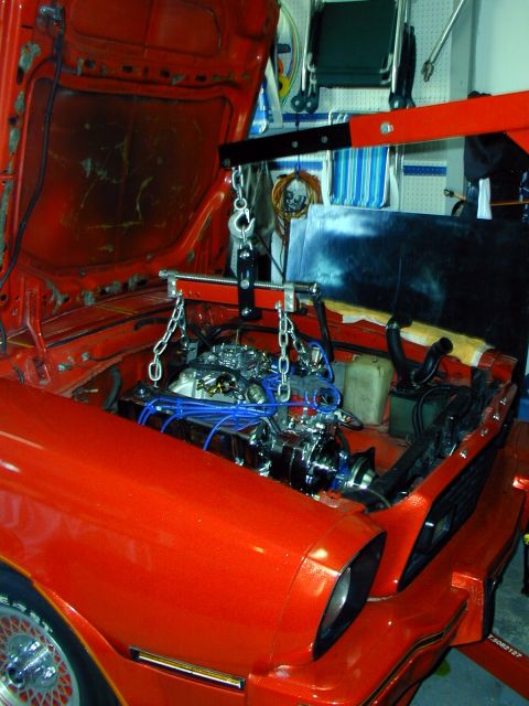 1978 Ford Mustang II - Engine hoist is positioned to lift the engine out of the engine bay of an orange 1978 Ford Mustang II.