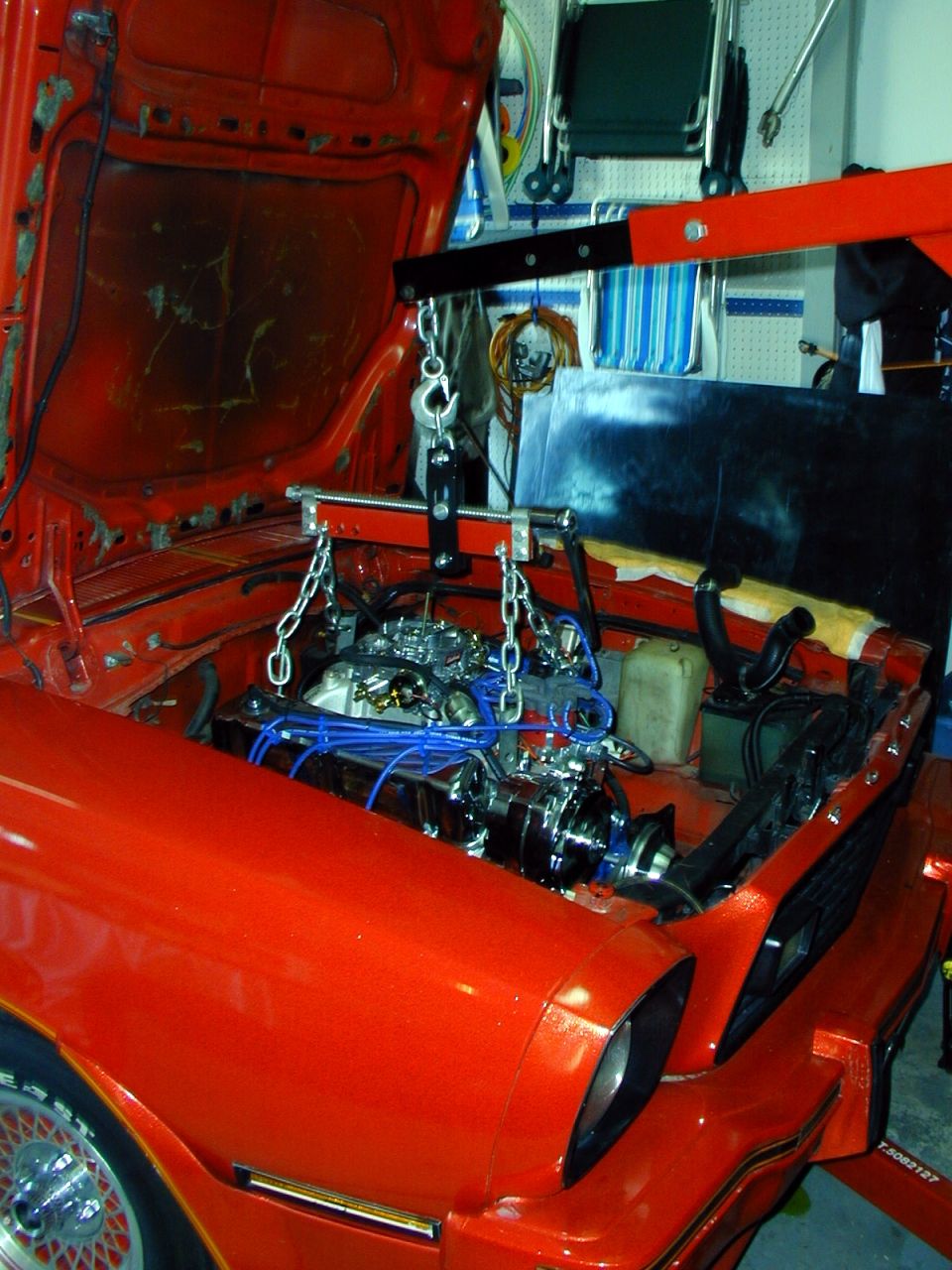 Orange 1978 Ford Mustang II engine bay with engine hoist lifting the engine