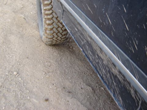 1991 Ford Bronco - Close-up view of a vehicle's side panel and tire, showing mud splatters and tread detail.