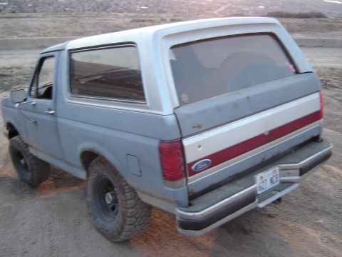 1991 Ford Bronco - This 1991 Ford Bronco is shown from the rear quarter angle, parked in an outdoor, dusty environment.
