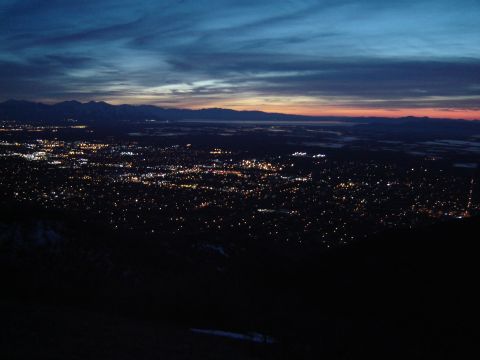 1991 Ford Bronco - A cityscape glows with lights as dusk settles, with distant mountains silhouetted against the colorful sky.
