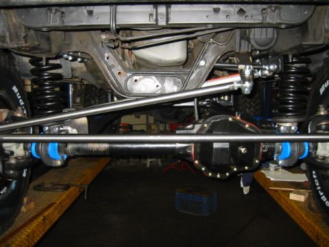 1992 Ford Bronco - Underside view looking rearward at a solid-axle front suspension conversion, with a Dana-style diff housing, coil springs, blue polyurethan…