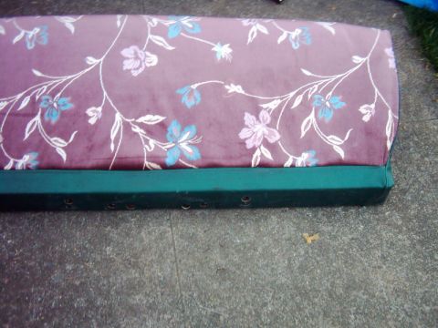 1978 Ford Bronco - A floral upholstered seat cushion with a green base is shown resting on a concrete surface.