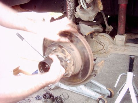 1978 Ford Bronco - Close-up view of a vehicle's brake rotor and suspension system, with a hand manipulating the rotor assembly.