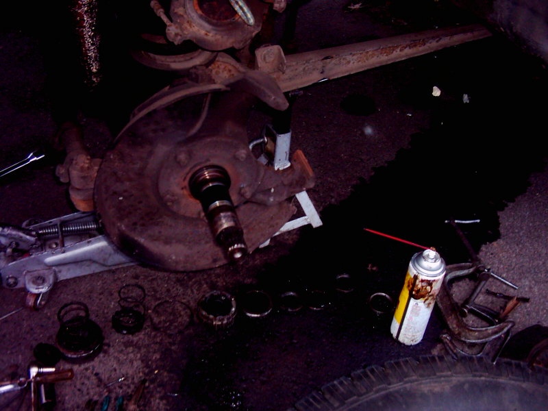 Disassembled brake rotor and hub assembly with tools and spray can on the ground