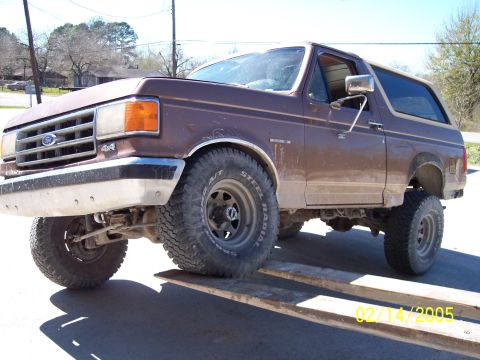 1987 Ford Bronco - This lifted 1987 Ford Bronco features a prominent 4x4 badge on its grille, indicating its off-road capabilities.