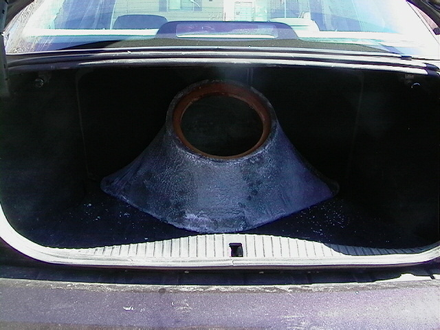 Cone-shaped fiberglass subwoofer enclosure with empty speaker ring in a sedan's trunk