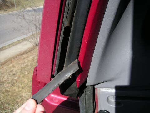 1994 Ford Bronco - A detached rubber seal is visible on the door frame of a red vehicle.