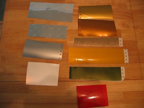 2002 Ford Taurus - Various paint swatches are laid out on a wooden surface, including gold, copper, yellow, green, red, and silver samples.