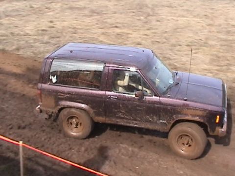 1994 Ford Explorer - Muddy 1989 Ford Bronco II navigating a dirt track during an event.