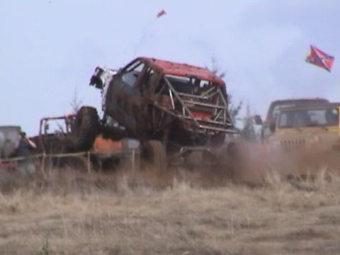 1994 Ford Explorer - A heavily modified off-road vehicle navigates a muddy terrain, with other vehicles visible in the background.