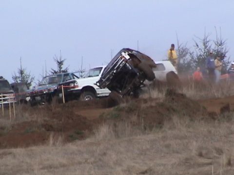 1994 Ford Explorer - Vehicles navigate a challenging off-road course, with one vehicle overturned in the mud.