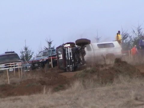 1994 Ford Explorer - Multiple vehicles are present in a muddy outdoor scene, with one SUV overturned on its side.