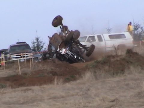 1994 Ford Explorer - Off-road vehicle flipped over during an event, with a white pickup truck in the background.