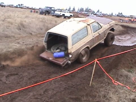 1994 Ford Explorer - This SUV, likely from the 1980s, is navigating a muddy course with its tailgate open.