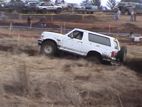 1994 Ford Explorer - A white Ford Bronco navigates a muddy off-road course during an event.