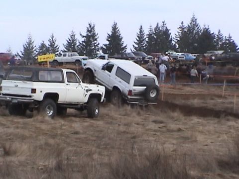 1994 Ford Explorer - Two off-road vehicles navigate a muddy course during an event.