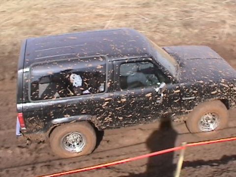 1994 Ford Explorer - This SUV is heavily covered in mud, indicating it's stuck in a muddy off-road situation.