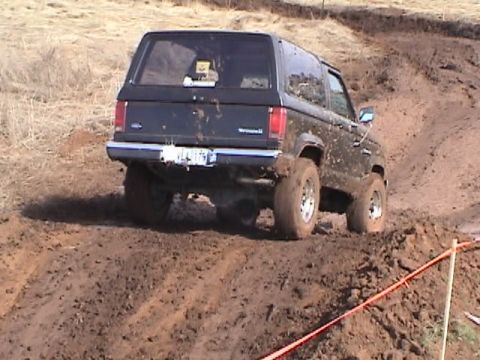 1994 Ford Explorer - A muddy black SUV navigates a challenging off-road course.