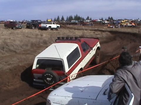 1994 Ford Explorer - A red and white 1994 Ford Explorer is stuck in a mud pit during an off-road event.