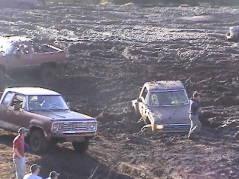 1994 Ford Explorer - Vehicles are stuck in a muddy field during an event.