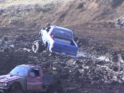 1994 Ford Explorer - Two pickup trucks are stuck in thick mud during an off-road event.