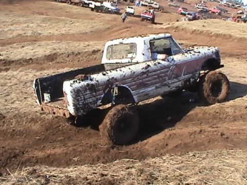 1994 Ford Explorer - Muddy pickup truck navigating a dirt course with other vehicles visible in the distance.