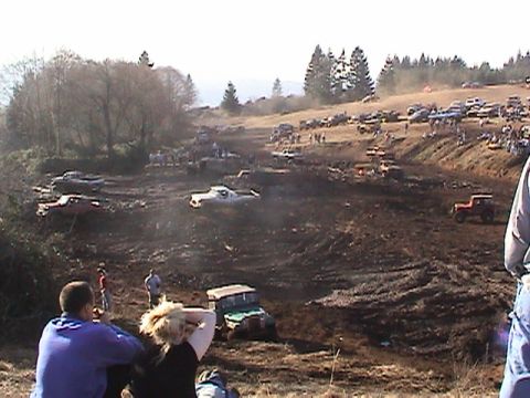 1994 Ford Explorer - Off-road vehicles navigate a mud pit during an event, with spectators observing from the sidelines.