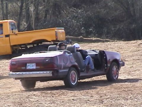 1994 Ford Explorer - A customized maroon convertible with its doors removed is seen with passengers, while a yellow truck is parked behind it.