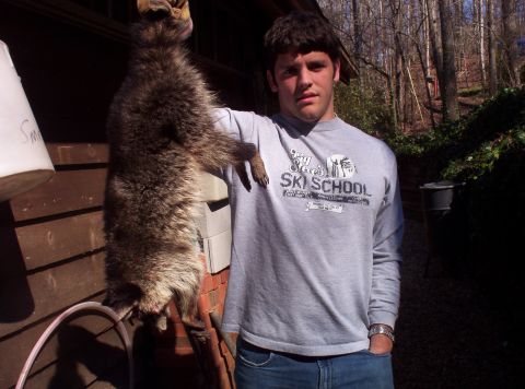1995 Ford Bronco - A man proudly displays a large raccoon he has caught, standing outdoors near a wooded area.