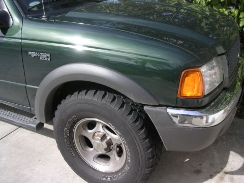 1985 Ford Bronco - Front corner of a green Ford Ranger pickup truck, showing the fender, wheel, and bumper.