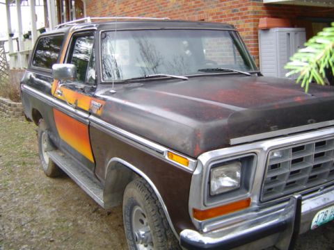 1979 Ford Bronco - This Ford Bronco has a distinctive sunset-themed stripe along its side and shows signs of wear on the hood.