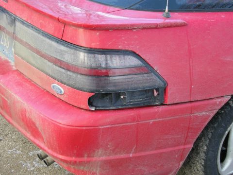 1990 Ford Probe - Close-up of a red car's rear section, showing the taillight and bumper.