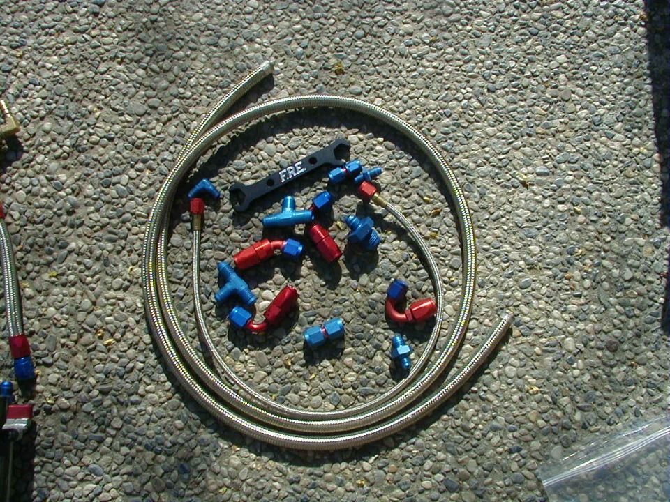assortment of red and blue AN fittings and braided fuel line with a FRE wrench