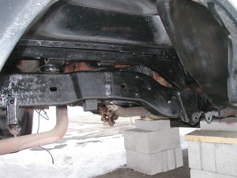 1994 Ford Bronco - The undercarriage of a vehicle is visible, with the frame and suspension components resting on concrete blocks.