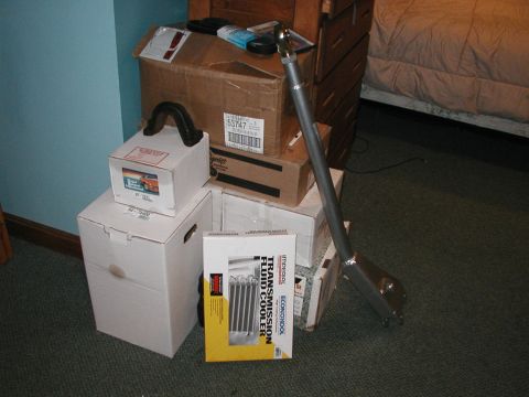 1994 Ford Bronco - Several automotive parts are stacked on the floor next to a bed.